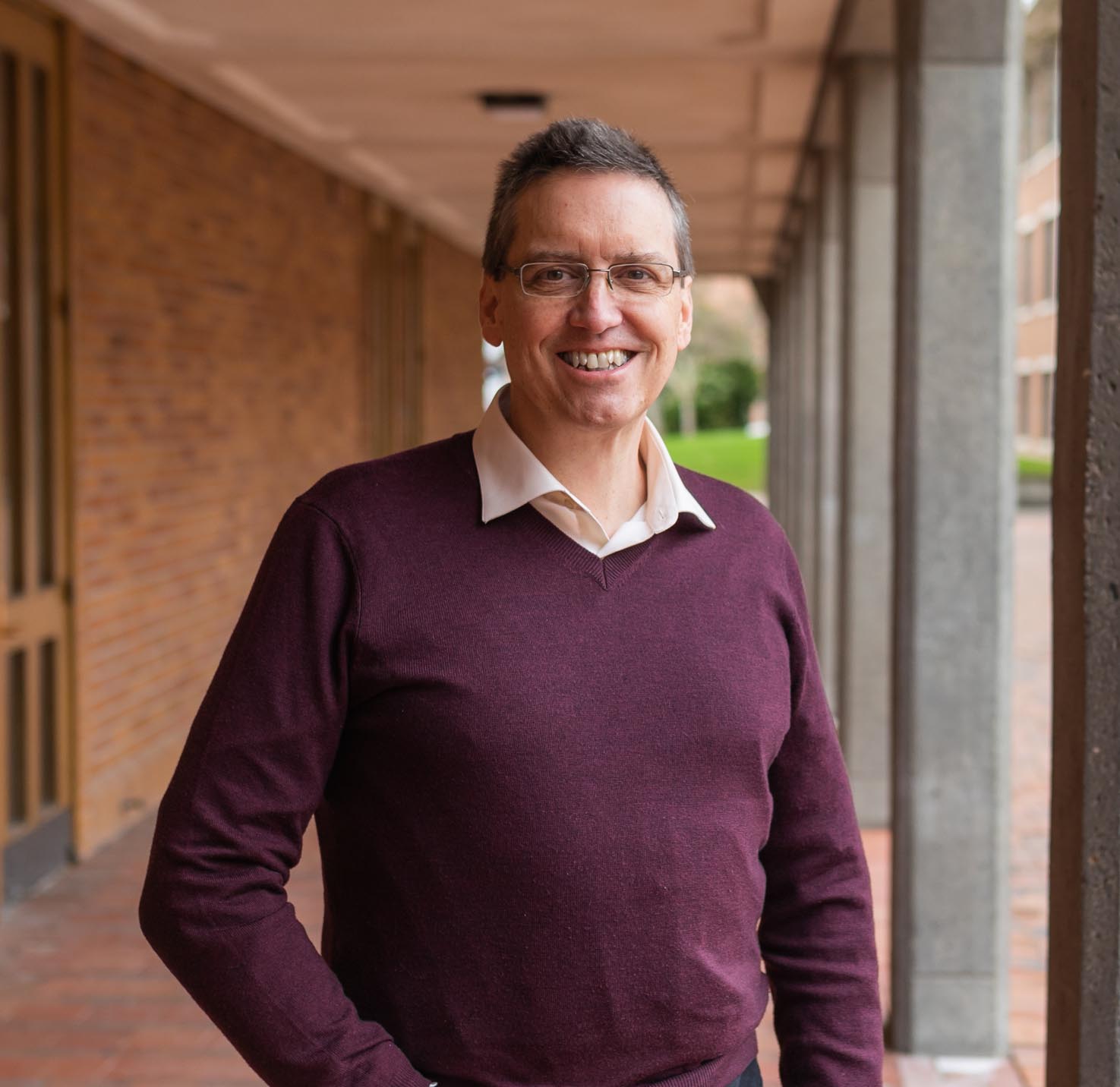 Brad Johnson standing next to Miller Hall, wearing a maroon sweater over a cream colored shirt