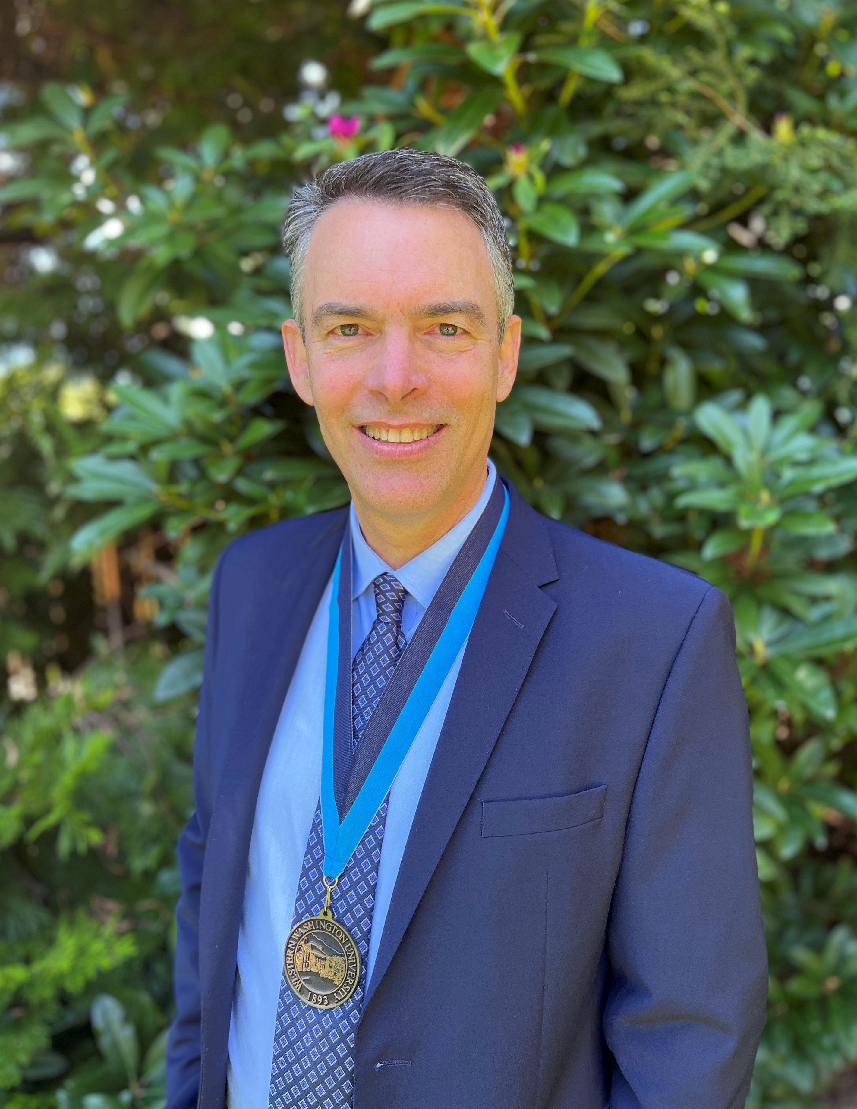 Photo of David Sattler wearing WWU award medallion with green trees in the background