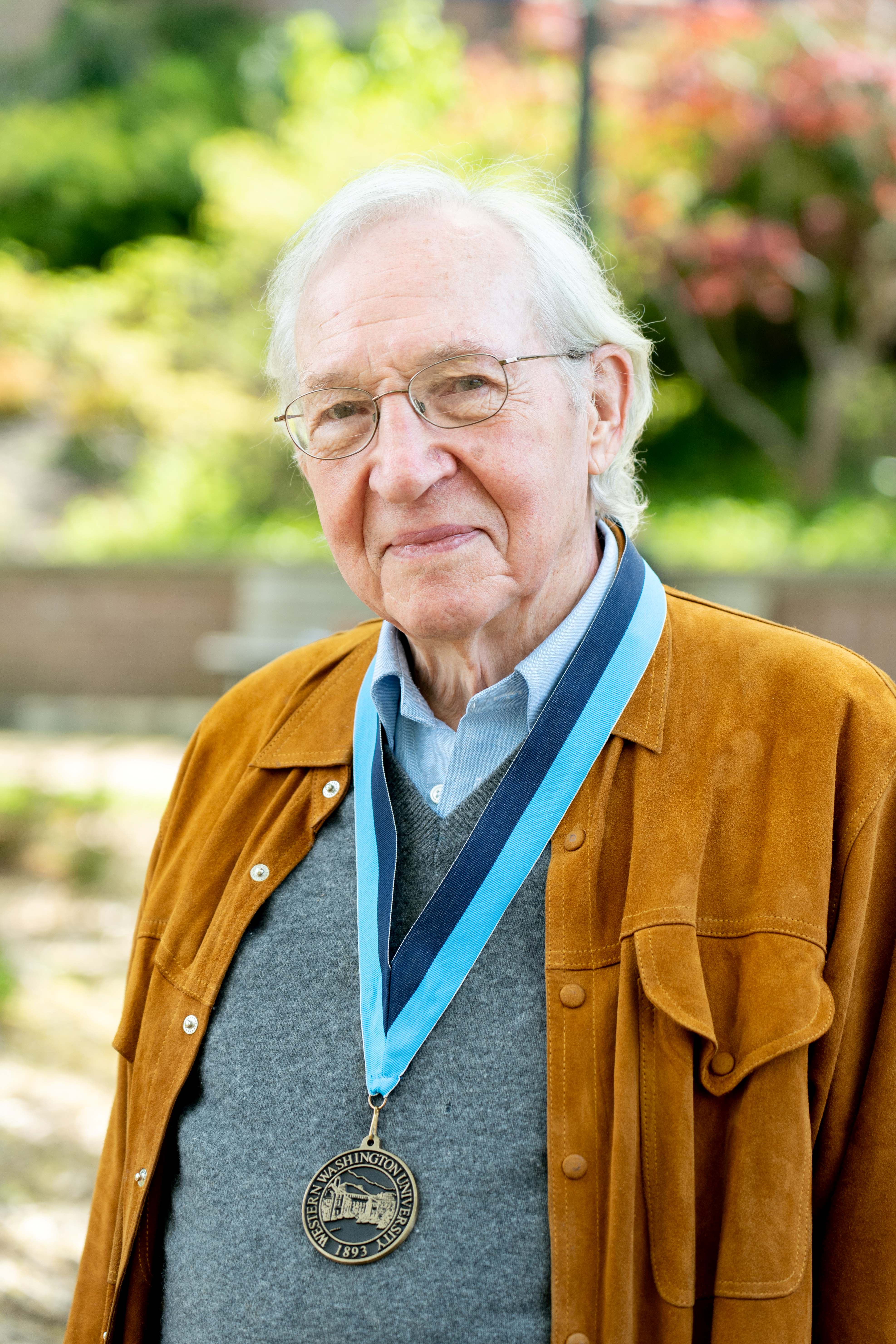 Professor Harris with a thoughful smile wearing an collared shirt and v-neck sweater and a WWU award medallion on a neck ribbon