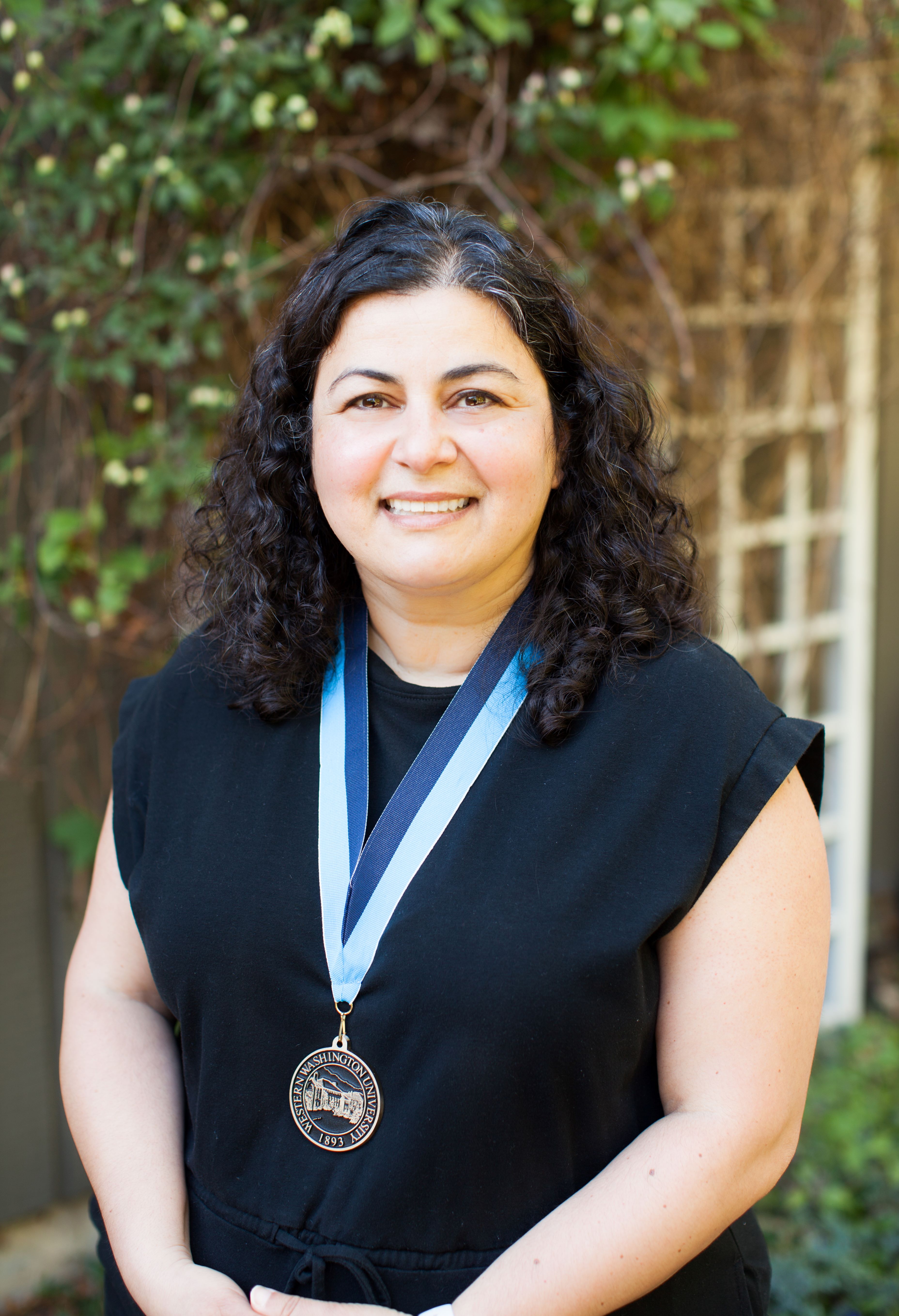 Shirin Deylami smiling warmly and wearing a black top and a WWU award medallion on a neck ribbom