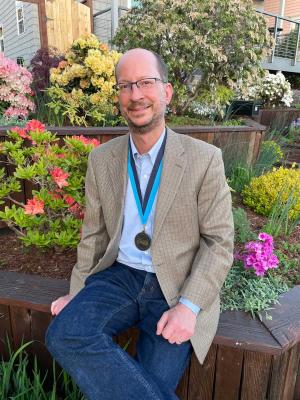Mark Bussell, Chemistry sits outside wearing his awards medal