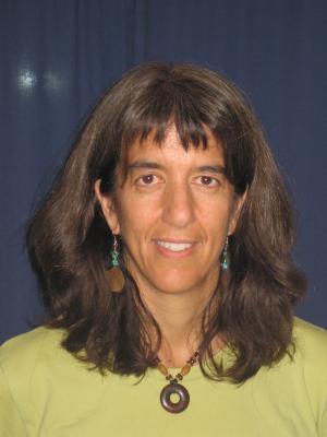 Susan DeBari smiling with a celery green shirt and a circular necklace