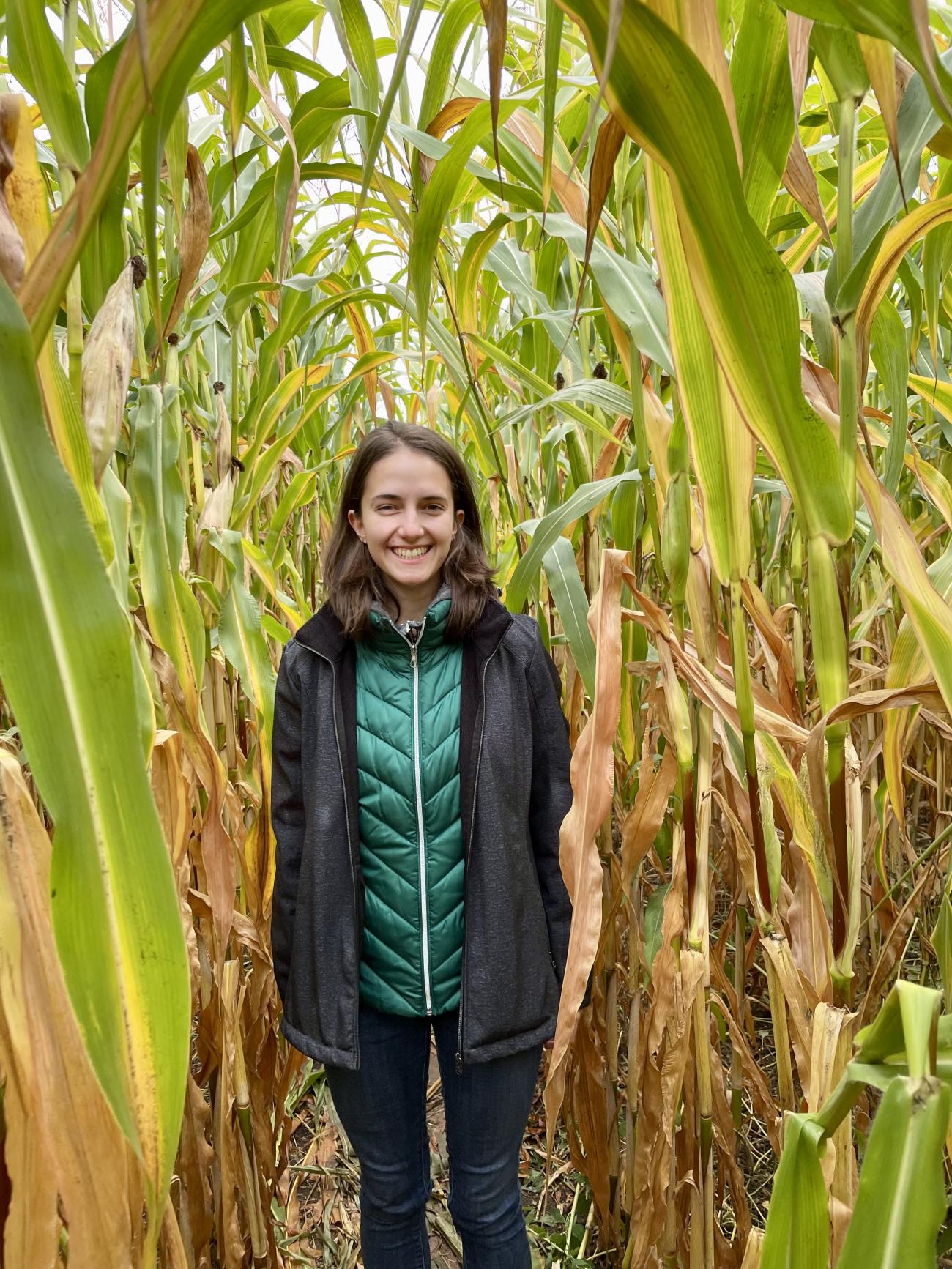 Rose Una stands smiling in a corn field