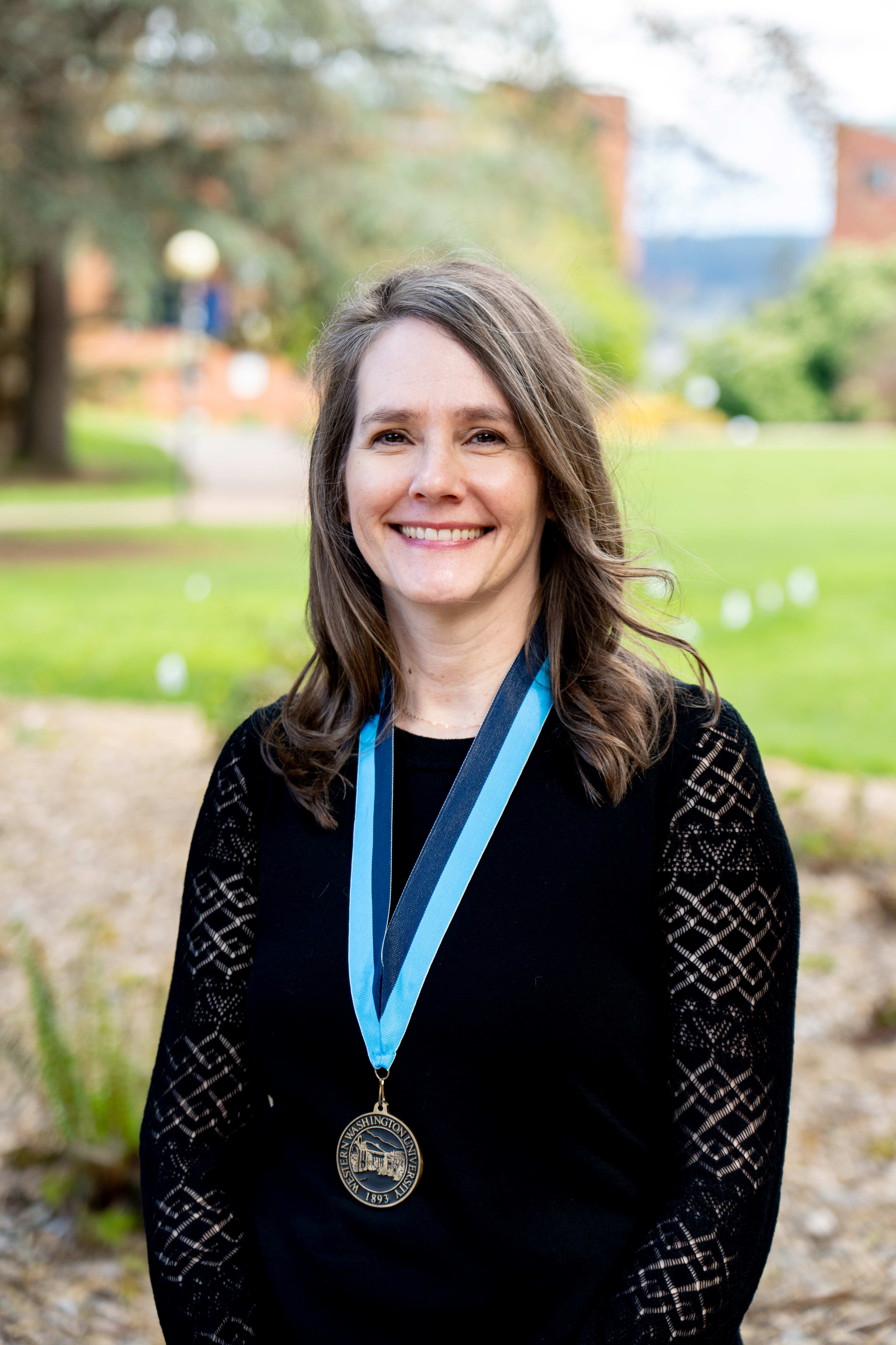Dr. Amanda Murphy smiling on Old Main Lawn wearing a WWU award medallion