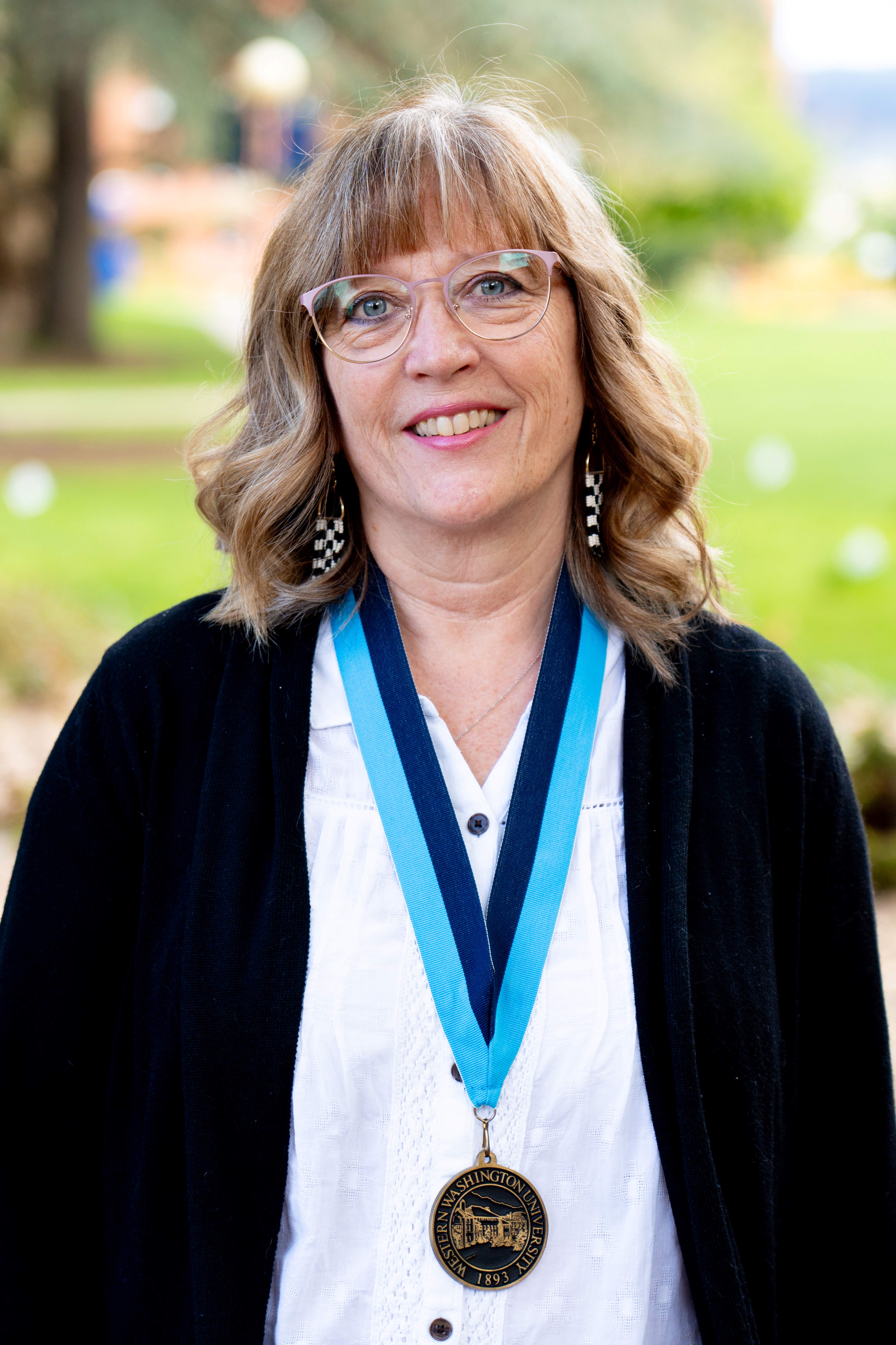 Diane Brearley stands on the Old Main Lawn wearing the WWU award medallion