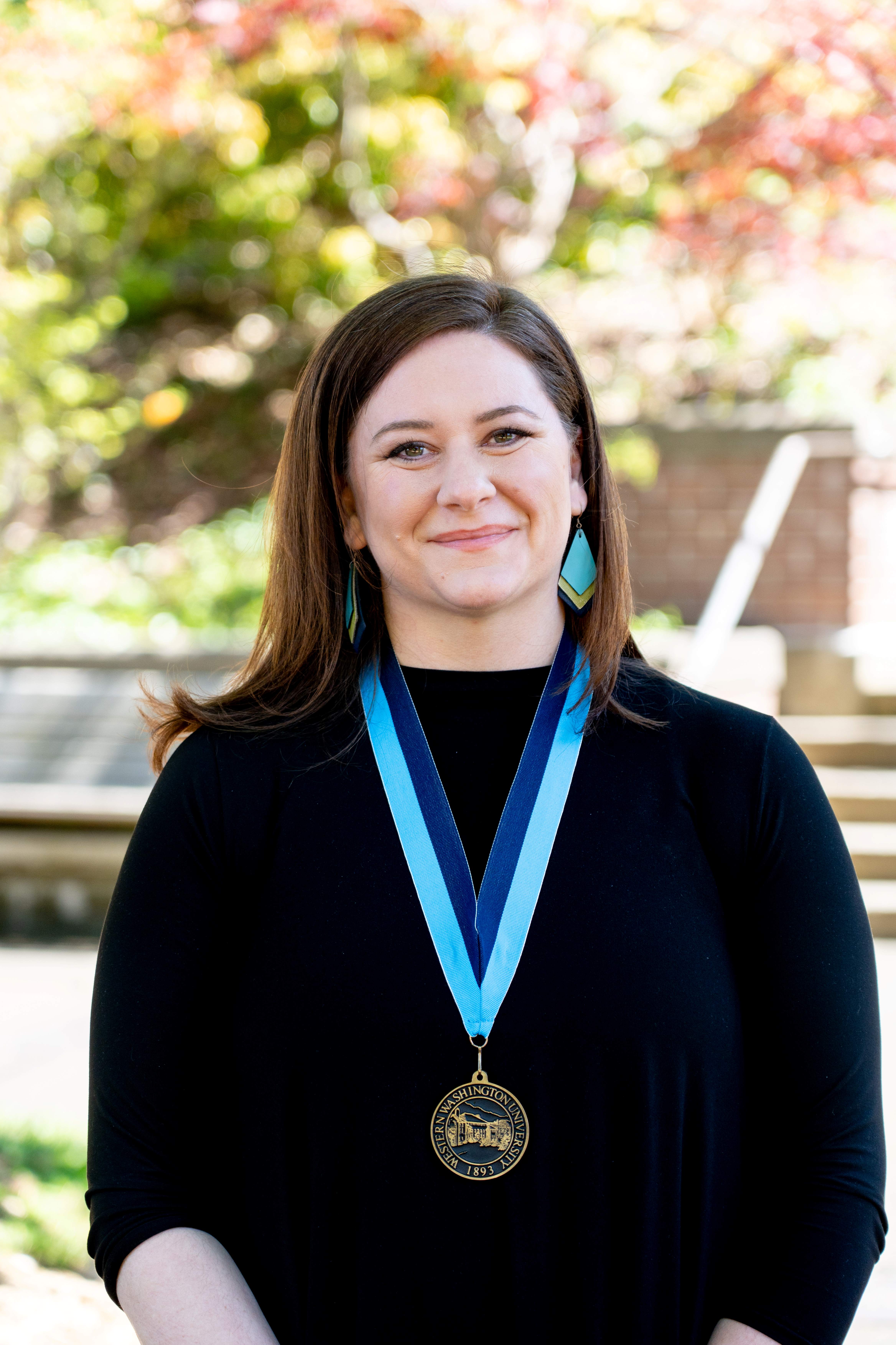 Maggie Savage in front of Old Main wearing a WWU award medallion